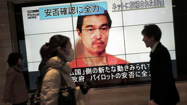 People walk by a screen showing TV news reports of Japanese hostage Kenji Goto, held by the Islamic State group, in Tokyo Saturday, Jan. 31, 2015 - Sputnik International