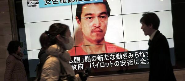 People walk by a screen showing TV news reports of Japanese hostage Kenji Goto, held by the Islamic State group, in Tokyo Saturday, Jan. 31, 2015 People walk by a screen showing TV news reports of Japanese hostage Kenji Goto, held by the Islamic State group, in Tokyo Saturday, Jan. 31, 2015 - Sputnik International