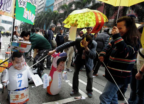 Protesters carrying yellow umbrellas, the symbol of the Occupy movement, play with a roly-poly toy mocking Hong Kong Chief Executive Leung Chun-ying during a march in Hong Kong February 1, 2015 - Sputnik International
