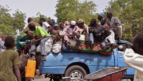 Villagers sit on the back of a small truck as they and others flee the recent violence near the city of Maiduguri, Nigeria - Sputnik International