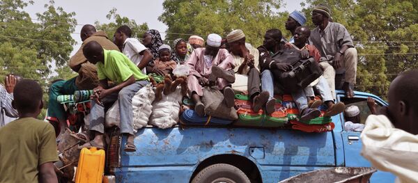 Villagers sit on the back of a small truck as they and others flee the recent violence near the city of Maiduguri, Nigeria - Sputnik International