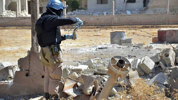 Member of UN investigation team taking samples of sands near a part of a missile that is likely to be one of the chemical rockets according to activists, in Damascus countryside of Ain Terma, Syria - Sputnik International