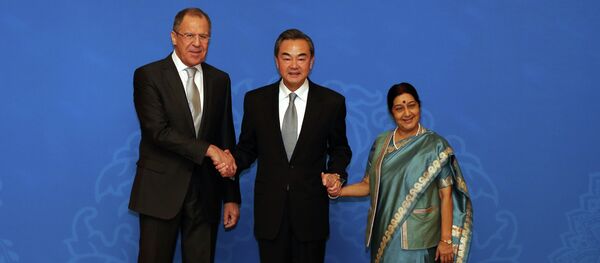 Russian Foreign Minister Sergei Lavrov (L), Chinese Foreign Minister Wang Yi (C) and Indian Foreign Minister Sushma Swaraj (R) shake hands as they for photographs before the thirteenth meeting of the Foreign Ministers of the China, Russia and India in Beijing on February 2, 2015 - Sputnik International