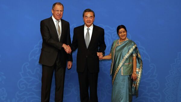 Russian Foreign Minister Sergei Lavrov (L), Chinese Foreign Minister Wang Yi (C) and Indian Foreign Minister Sushma Swaraj (R) shake hands as they for photographs before the thirteenth meeting of the Foreign Ministers of the China, Russia and India in Beijing on February 2, 2015 - Sputnik International