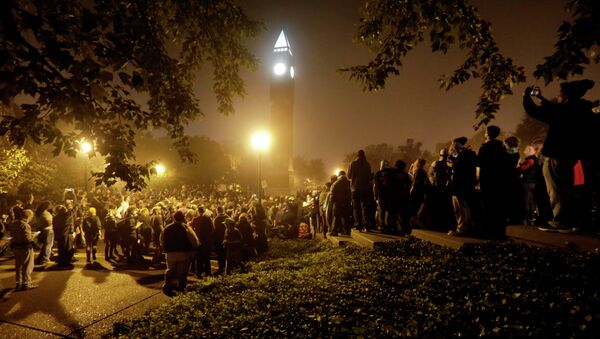 Protesters gather around the St. Louis University campus clock tower after a march through the streets of St. Louis, protesting against the recent shootings of two young black men by law enforcement officers, early Monday, Oct. 13, 2014. - Sputnik International