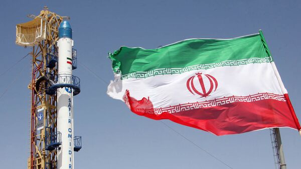 Iranian flag fluttering in front of Iran's Safir Omid rocket, which is capable of carrying a satellite into orbit. File photo  - Sputnik International