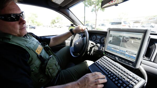 San Diego County Deputy Sheriff Ben Chassen looks at a monitor as his vehicle reads the license plates of cars in a parking lot. - Sputnik International