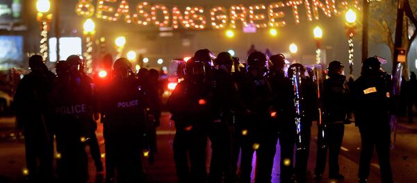 Police in riot gear use tear gas to clear the street in front of the Ferguson Police Department after the announcement of the grand jury decision not to indict police officer Darren Wilson in the fatal shooting of Michael Brown, an unarmed black 18-year-old, Monday, Nov. 24, 2014, in Ferguson, Mo. - Sputnik International
