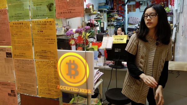 A staff member from a travel agency displays a Bitcoin logo as they accept bitcoins for payment in Hong Kong Friday, Feb. 28, 2014, after the world's first bitcoin retail store opened in Hong Kong, despite the virtual currency facing much scrutiny. - Sputnik International