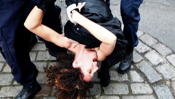 A Femen activist is taken away by police officers as she protests Tuesday, Feb. 10, 2015 in front of the Lille courthouse in Lille, northern France, where Dominique Strauss-Kahn goes on trial for sex charges in France. - Sputnik International