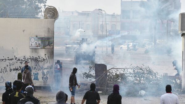 Protesters take cover from tear gas fired by riot police during early morning clashes, on the fourth anniversary of an uprising to demand democratic reforms in the U.S.-allied Gulf Arab state, in the village of Sanabis, west of Manama - Sputnik International