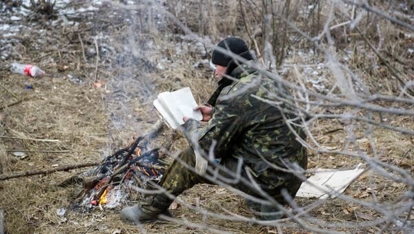 A Ukrainian serviceman reads a book as he warms himself by a camp fire in Svitlodarsk, approaching Debaltseve on February 15, 2015 - Sputnik International