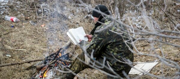 A Ukrainian serviceman reads a book as he warms himself by a camp fire in Svitlodarsk, approaching Debaltseve on February 15, 2015 - Sputnik International