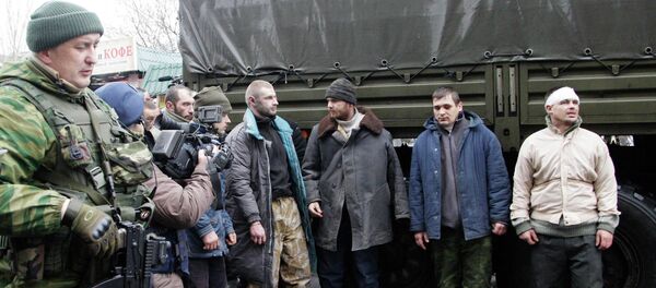 Prisoners of war (POWs), representing Ukrainian armed forces and escorted by members of the armed forces of the separatist self-proclaimed Donetsk People's Republic, line up as they visit a site near the public transport stop, where civilians were earlier killed on Thursday, in Donetsk, January 22, 2015. File photo. - Sputnik International