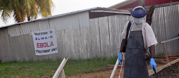 A health care worker sprays disinfectant outside a USAID, funded Ebola clinic in Monrovia, Liberia, Friday, Jan. 30, 2015 - Sputnik International
