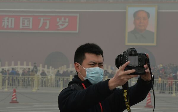 A Chinese tourists takes a photo while wearing a face mask in Tiananmen Square as heavy air pollution continues to shroud Beijing on February 26, 2014 - Sputnik International