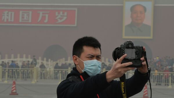 A Chinese tourists takes a photo while wearing a face mask in Tiananmen Square as heavy air pollution continues to shroud Beijing on February 26, 2014 - Sputnik International