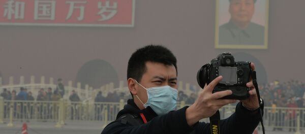 A Chinese tourists takes a photo while wearing a face mask in Tiananmen Square as heavy air pollution continues to shroud Beijing on February 26, 2014 - Sputnik International
