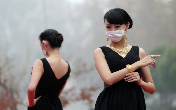 This picture taken on December 7, 2013 shows models wearing surgical masks as they parade a collection of gold jewelleries at a park in Nanjing, east China's Jiangsu province - Sputnik International