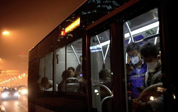 Commuters wearing masks to protect themselves from pollutants check smartphones as they ride on a bus on a hazy day in Beijing, China Monday, Oct. 20, 2014 - Sputnik International