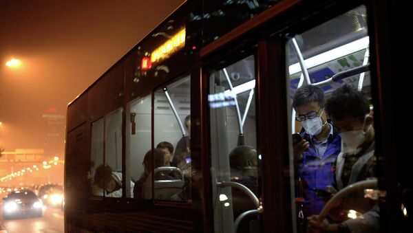 Commuters wearing masks to protect themselves from pollutants check smartphones as they ride on a bus on a hazy day in Beijing, China Monday, Oct. 20, 2014 - Sputnik International