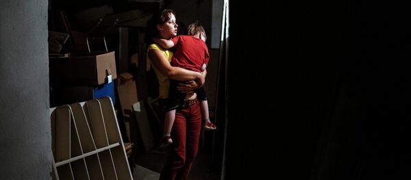 A woman holds her child in her arms as they are hidding in a bomb shelter in an orphanage during a shelling in the town of Makiyivka on August 19, 2014 A woman holds her child in her arms as they are hidding in a bomb shelter in an orphanage during a shelling in the town of Makiyivka on August 19, 2014 - Sputnik International