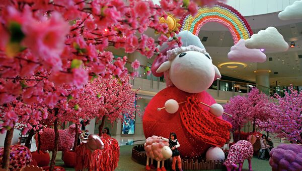 A girl touches a goat decoration as a shopping mall floor is decorated with goat installation to celebrate the upcoming Chinese Lunar New Year in Hong Kong - Sputnik International