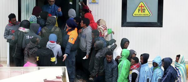 Migrants stand in front of the infirmary at the immigration centre on the southern Italian island of Lampedusa - Sputnik International