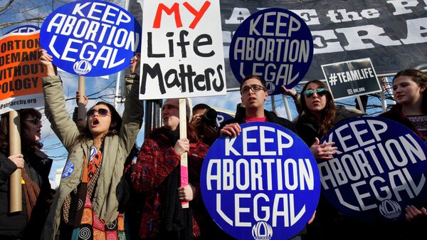 Abortion rights advocates hold signs while anti-abortion demonstrators walk by during the annual March for Life in Washington, DC. - Sputnik International