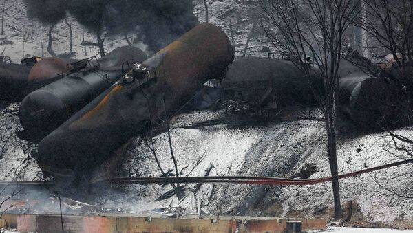 The charred remains of a house and a vehicle are shown below a derailed CSX Corp train in Mount Carbon, West Virginia - Sputnik International