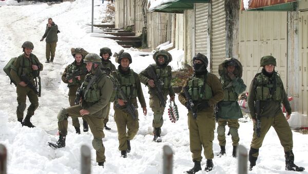 Israeli soldiers walk down a snow covered road in the West Bank town of Hebron - Sputnik International