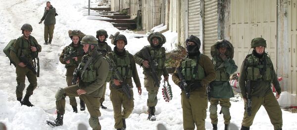 Israeli soldiers walk down a snow covered road in the West Bank town of Hebron Israeli soldiers walk down a snow covered road in the West Bank town of Hebron - Sputnik International