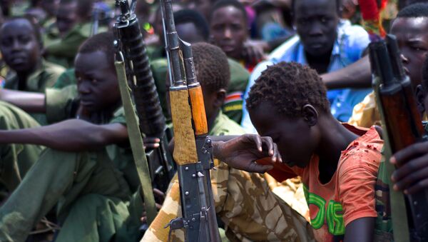 Children soldiers sit on February 10, 2015 with their rifles at a ceremony of the child soldiers disarmament, demobilisation and reintegration in South Sudan. - Sputnik International