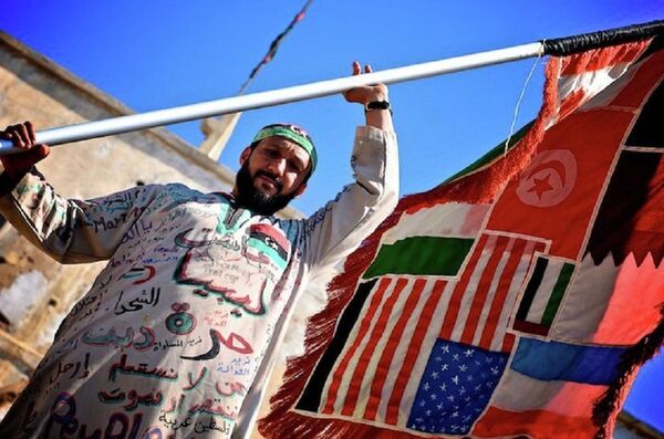 A man holds a flag of countries involved in the Libyan Civil War. - Sputnik International