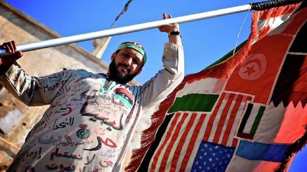 A man holds a flag of countries involved in the Libyan Civil War. - Sputnik International