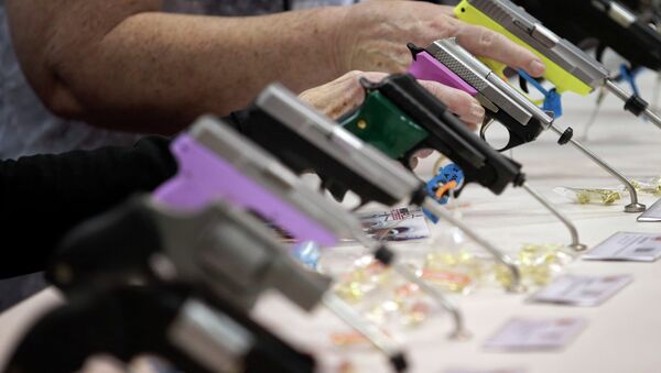 Attendees look over a pistol display at the National Rifle Association's annual convention. - Sputnik International