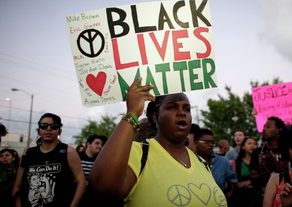 Desiree Griffiths, 31, of Miami, holds up a sign saying Black Lives Matter, with the names of Michael Brown and Eric Garner, two black men recently killed by police, during a protest - Sputnik International