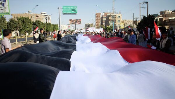 Pro-Houthi protesters carry a Yemeni flag as they march during a demonstration against the U.S. and the U.N. Security Council in Sanaa February 20, 2015 - Sputnik International