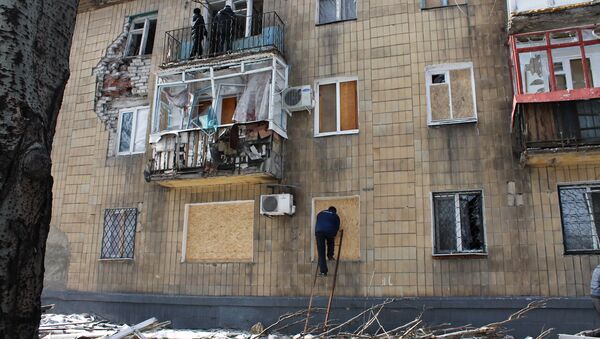 A man covers windows in a building which was damaged by shelling in Donetsk - Sputnik International