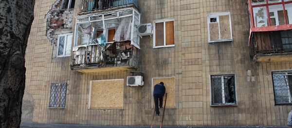 A man covers windows in a building which was damaged by shelling in Donetsk - Sputnik International