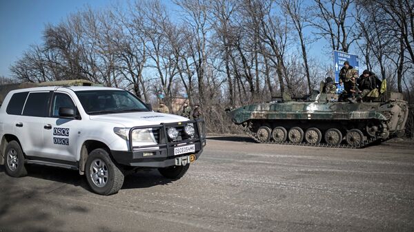 A car of Organization for Security and Co-operation in Europe (OSCE) mission drives past a Ukrainian military vehicle near Artemivsk, eastern Ukraine - Sputnik International