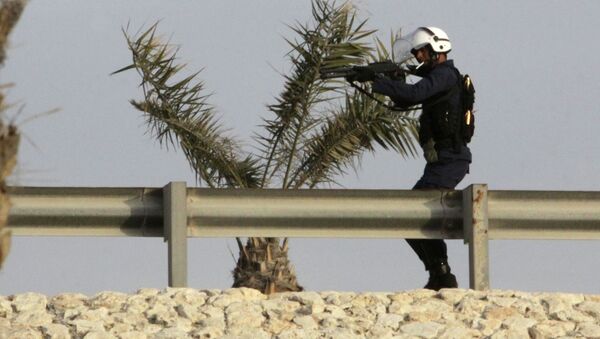 A riot policeman takes aim from a highway overpass at Bahraini anti-government protesters below - Sputnik International
