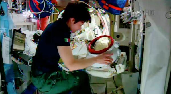 In this screenshot from a video provided by NASA, Italian astronaut Samantha Cristoforetti checks the helmet of American astronaut Terry Virts inside the International Space Station on Wednesday. In this screenshot from a video provided by NASA, Italian astronaut Samantha Cristoforetti checks the helmet of American astronaut Terry Virts inside the International Space Station on Wednesday. - Sputnik International