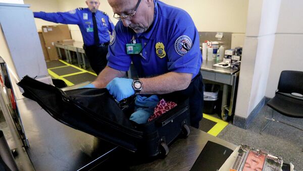 A TSA agent checks a bag at a security checkpoint area at Midway International Airport in Chicago. - Sputnik International