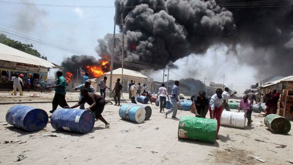 People push oil barrels away from the site of an explosion at a petrol station and storage facility near the Bakara open-air market in Somalia's capital Mogadishu, February 23, 2015 - Sputnik International