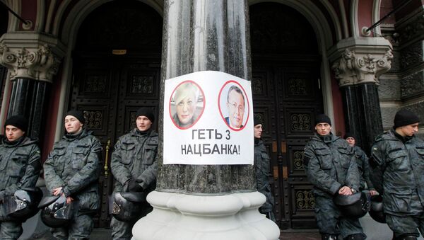 Policemen stay at the entrance of Ukraine's central bank office behind a poster depicting bank chief Valeria Gontareva (L) and the bank's first deputy Oleksandr Pysaruk in Kiev - Sputnik International