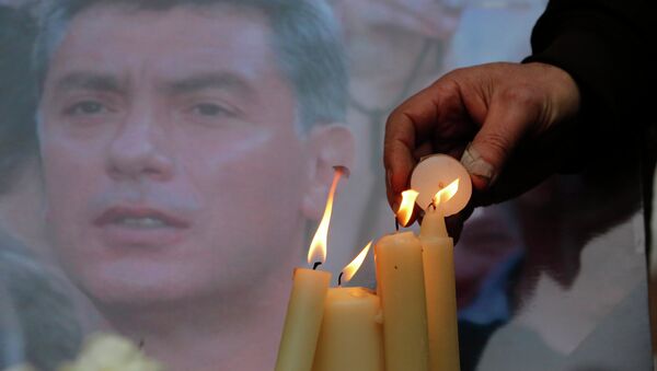 People light candles in memory of Boris Nemtsov, seen behind, at the monument of political prisoners 'Solovetsky Stone' in central St.Petersburg, Russia, Saturday, Feb. 28, 2015. - Sputnik International