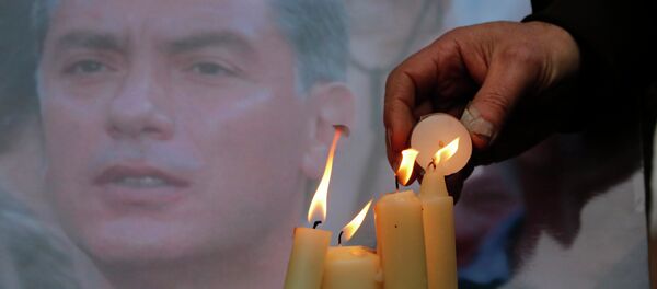 People light candles in memory of Boris Nemtsov, seen behind, at the monument of political prisoners 'Solovetsky Stone' in central St.Petersburg, Russia, Saturday, Feb. 28, 2015. - Sputnik International
