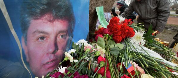 People lay flowers in memory of Boris Nemtsov, seen at left, at the monument of political prisoners 'Solovetsky Stone' in central St. Petersburg, Russia, Saturday, Feb. 28, 2015. - Sputnik International