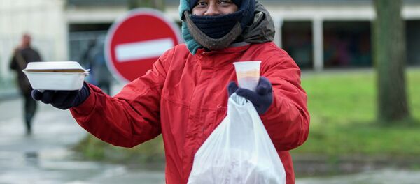 A migrant holds up hot food received from the association La Vie Active in Calais on January 15, 2015, at the site where a new day center for migrants was opened. A migrant holds up hot food received from the association La Vie Active in Calais on January 15, 2015, at the site where a new day center for migrants was opened. - Sputnik International